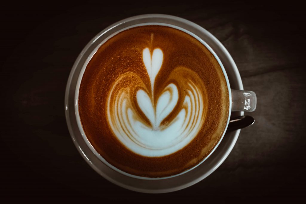 Top view of a cappuccino featuring elegant heart-shaped latte art in a ceramic cup.